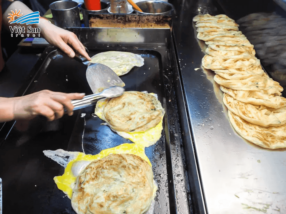 Bánh hành chiên vàng giòn trên chảo nóng.