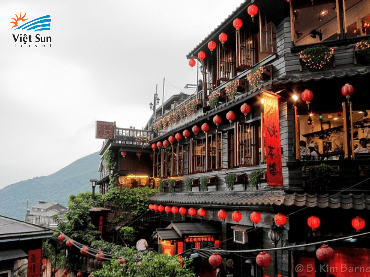 Ban công A-Mei Tea House nhìn xuống biển và dãy núi xanh mờ.