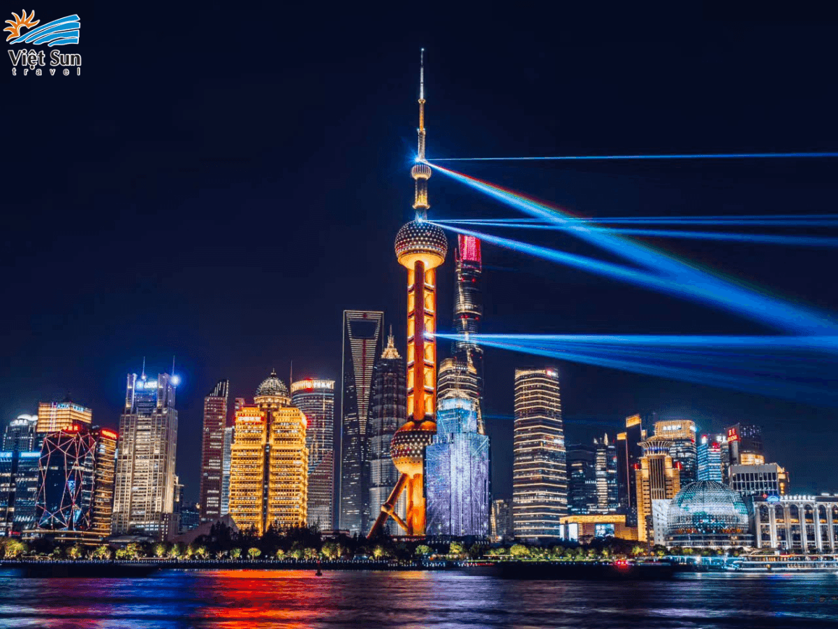 Bến Thượng Hải về đêm nổi bật với ánh đèn rực rỡ và skyline hiện đại của Phố Đông bên kia sông.png