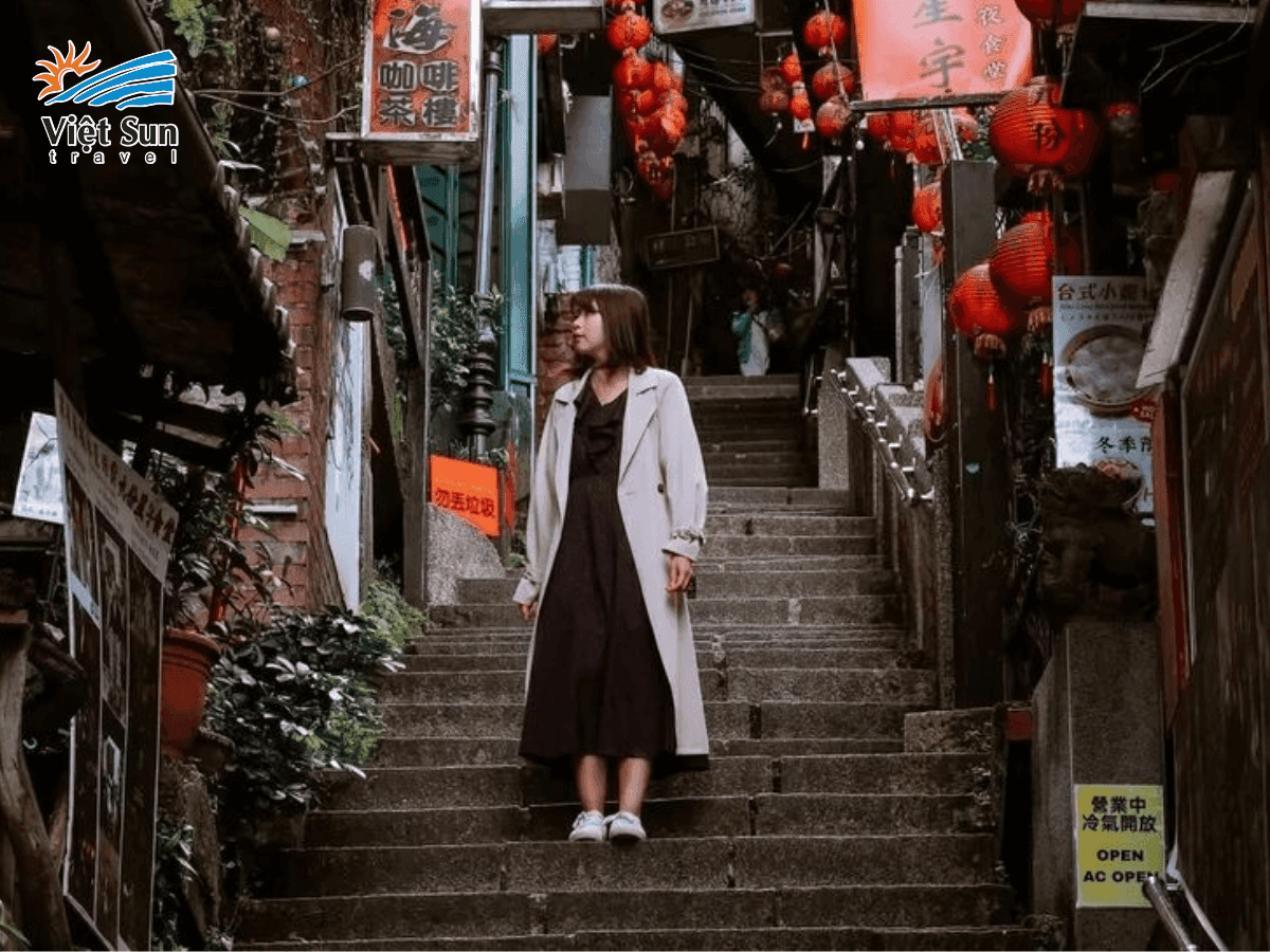 Du khách chụp ảnh giữa bậc thang lát đá, nền là hàng quán cổ kính.
